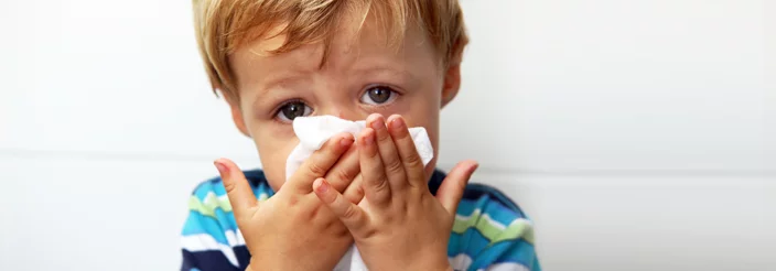 Niño pequeño sonándose la nariz