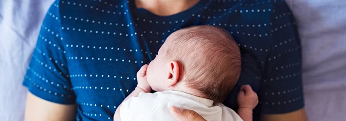 Bebé tumbado boca abajo encima de su padre