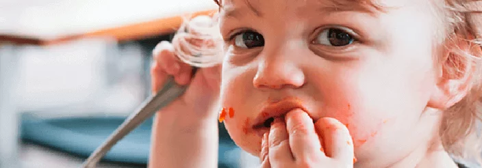 Niño pequeño comiendo con las manos