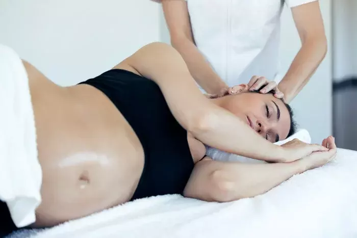 Mujer embarazada tumbada recibiendo un masaje para la cefalea